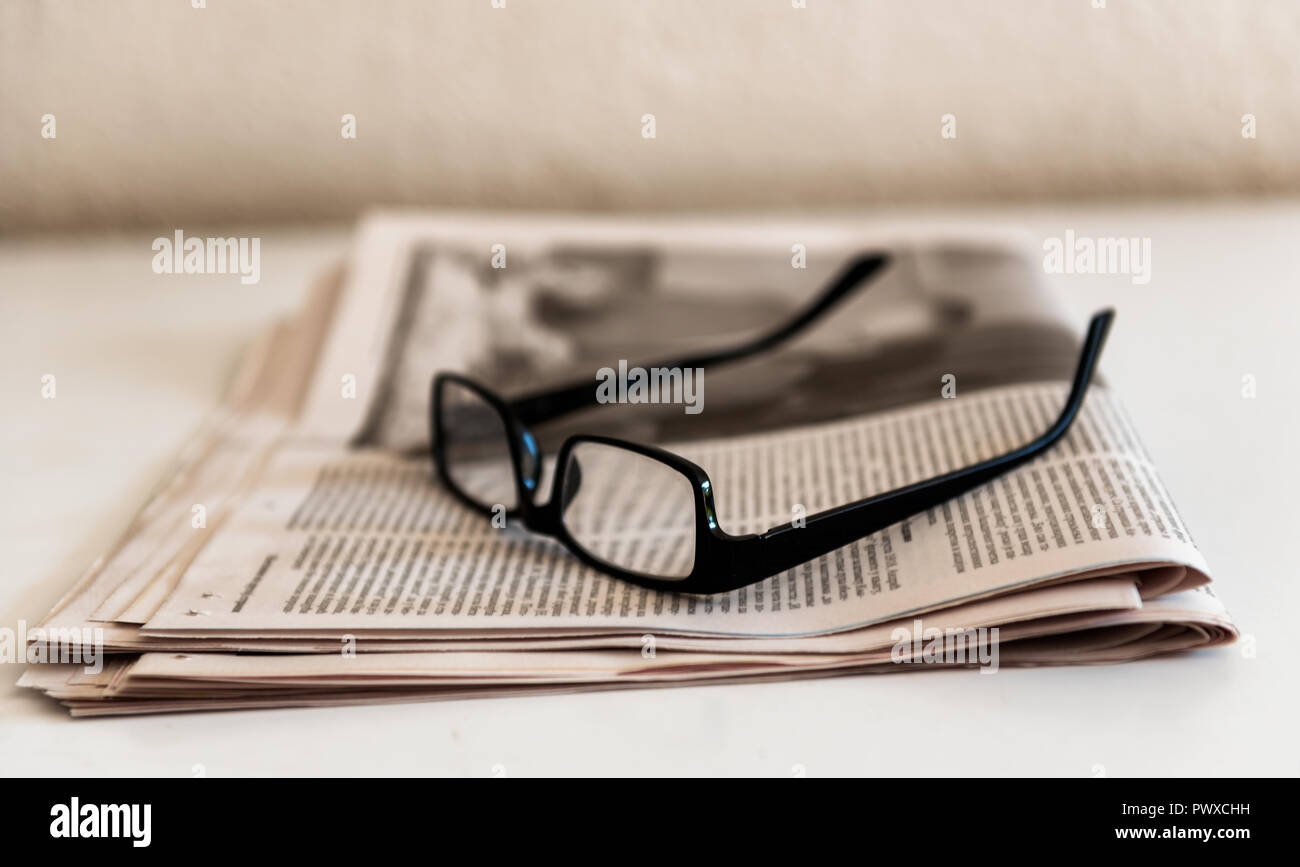 Old Spectacles or Glasses and Newspapers On a White Table Old Spectacles or Glasses and Newspapers On a White Table Stock Photo