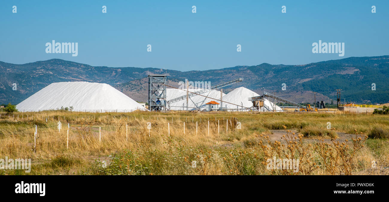 Mountains of salt being harvested with heavy machinery and conveyor belts Stock Photo