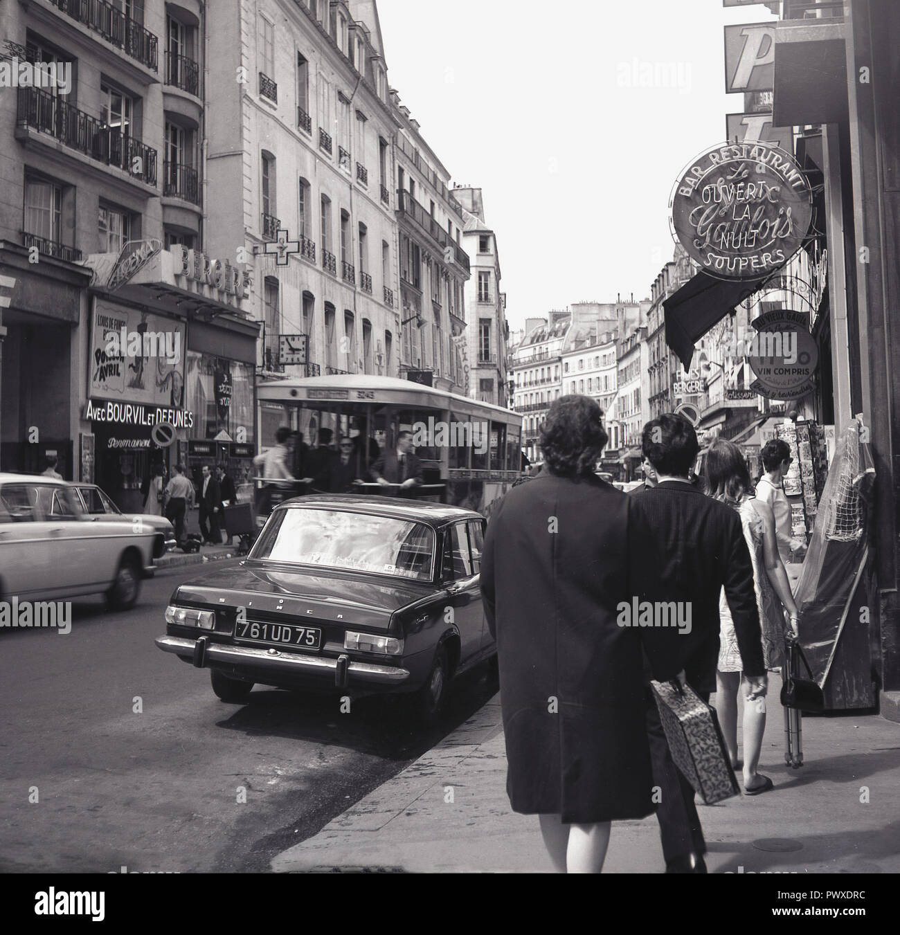 1954, historical, busy street in Paris, France, rue richer with the Bergere cinema, showing the french comedy film, 'April Fool's Day' or 'Poisson d'Avril', staring Andre Bourvil and Louis de Funes. Stock Photo