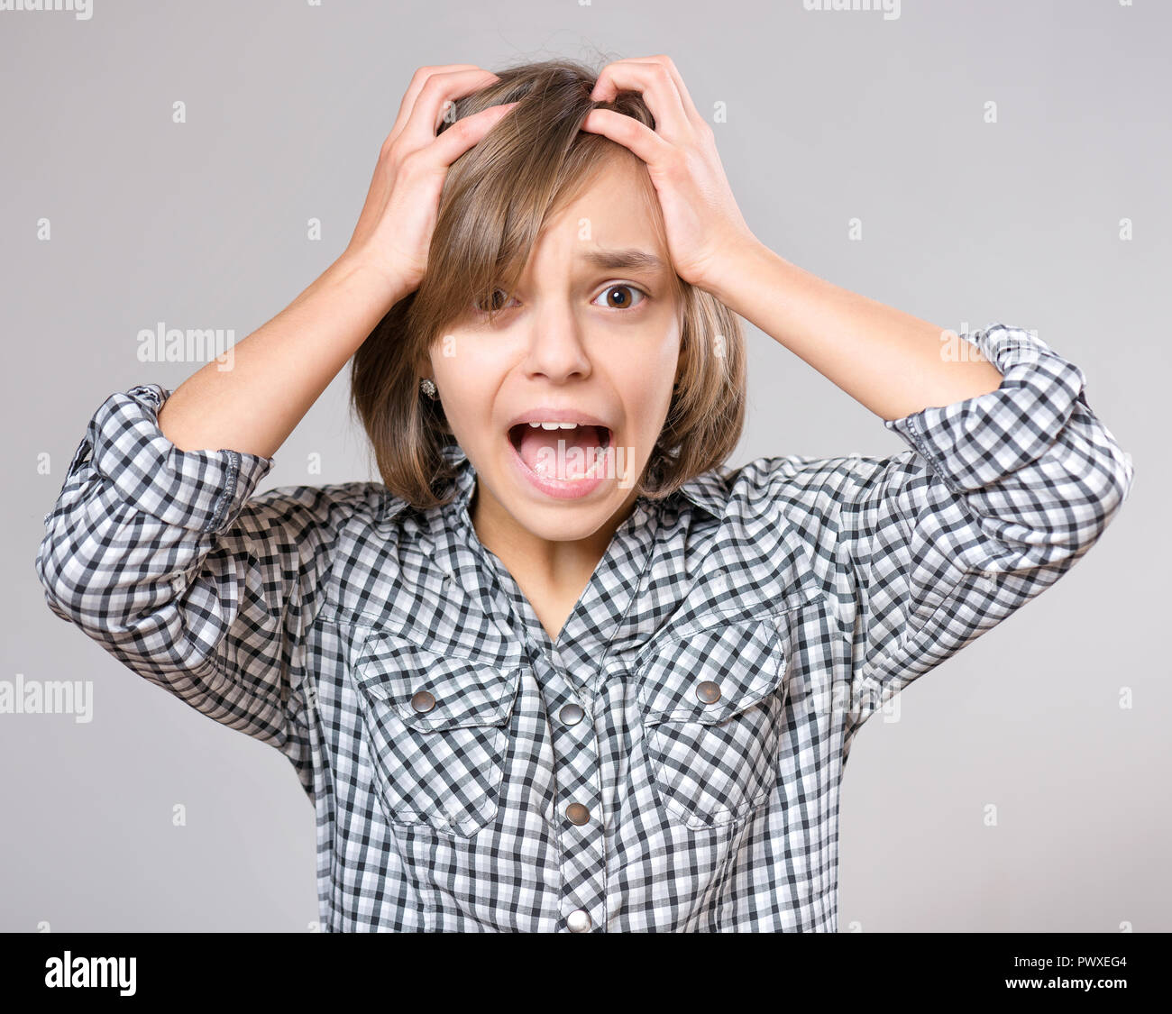 Close-up emotional portrait of excited little girl. Funny cute surprised child 10 year old with mouth open in amazement. Shocked teenager, on gray bac Stock Photo