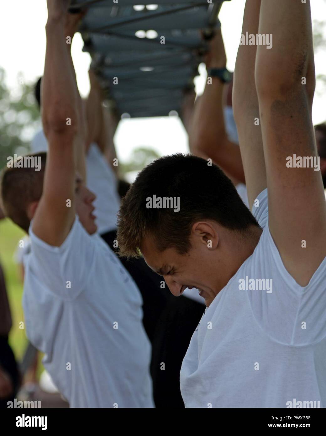 U.S. Naval Sea Cadet Corps cadets perform pull-ups during a physical readiness test at Tyndall Air Force Base, Fla., June 25, 2017. Cadets must consistently pass a rigorous physical test that includes a timed 500 meter swim, six pull-ups, 42 push-ups and 50 sit-ups within 2 minutes and a timed 1.5 mile run. The USNSCC program utilized Tyndall’s base resources periodically over the course of two weeks while testing and training its cadets in naval special warfare courses. Stock Photo