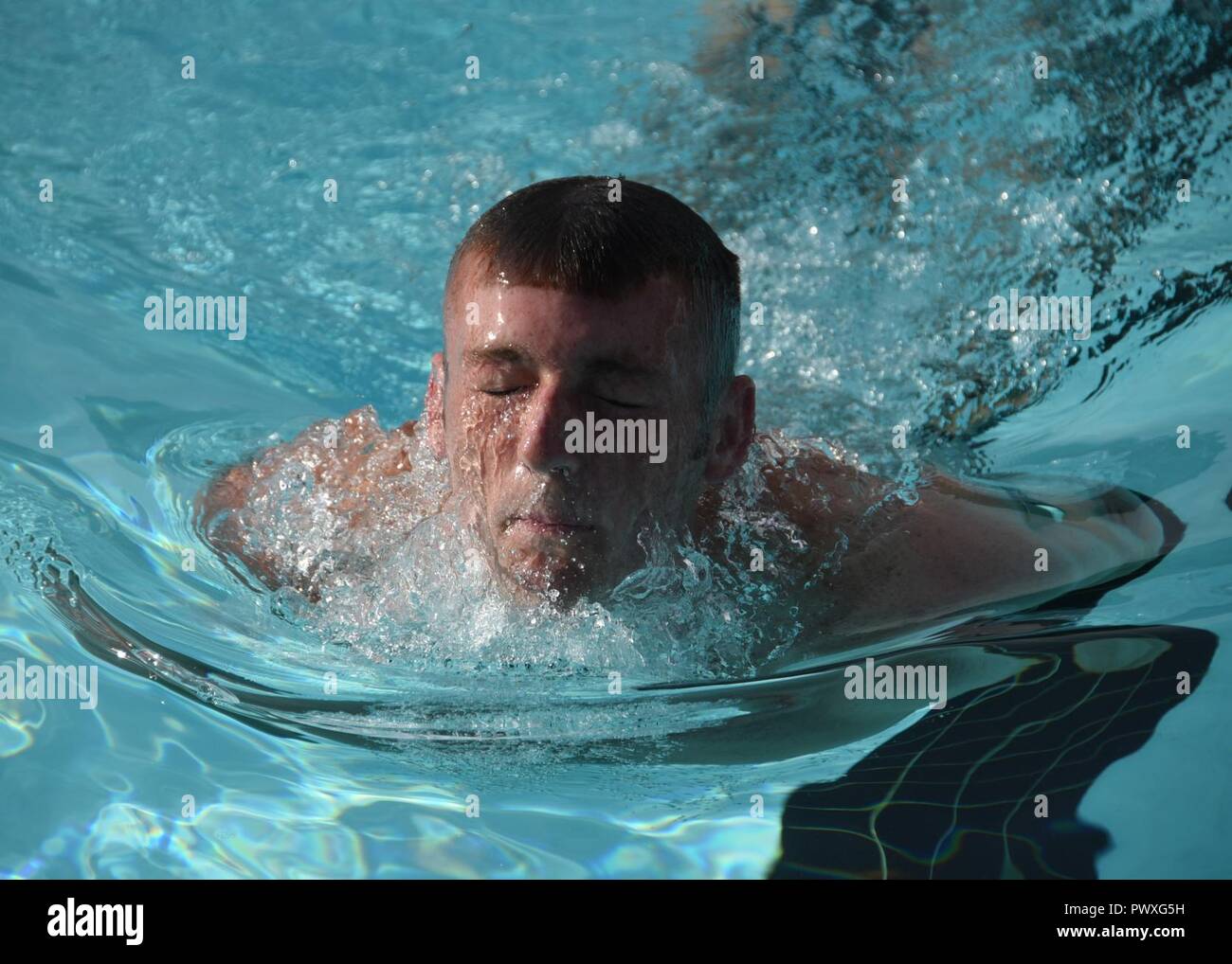 A U.S. Naval Sea Cadet Corps cadet emerges from the water during the swimming portion of a physical readiness test at Tyndall Air Force Base, Fla., June 25, 2017. Cadets must consistently pass a rigorous physical test that includes a timed 500 meter swim using only a side or breaststroke. The USNSCC program utilized Tyndall’s base resources periodically over the course of two weeks while testing and training its cadets in naval special warfare courses. Stock Photo