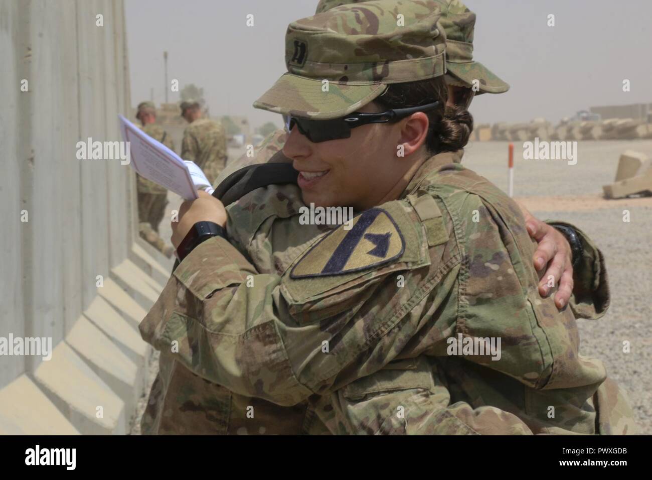 U.S. Army Capt. Kaitlin Whitmore, commander of Charlie Company, 215th Brigade Support Battalion, 3rd Armored Brigade Combat Team, 1st Cavalry Division, hugs her brother, U.S. Army Capt. Scott Rayburn, commander of Alpha Company, 37th Engineer Battalion, 2nd Brigade Combat Team, 82nd Airborne Division, at his change-of-command ceremony in Qayyarah West Airfield, Iraq, July 1, 2017. The siblings, who hail from Gainesville, Florida, both attended ROTC in college and were even commissioned during the same week in 2011. Stock Photo