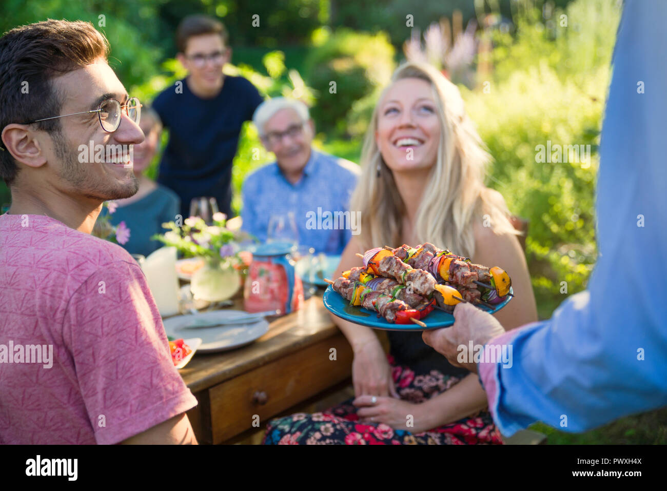 cheerful family gathered around a table for a bbq in the garden Stock Photo