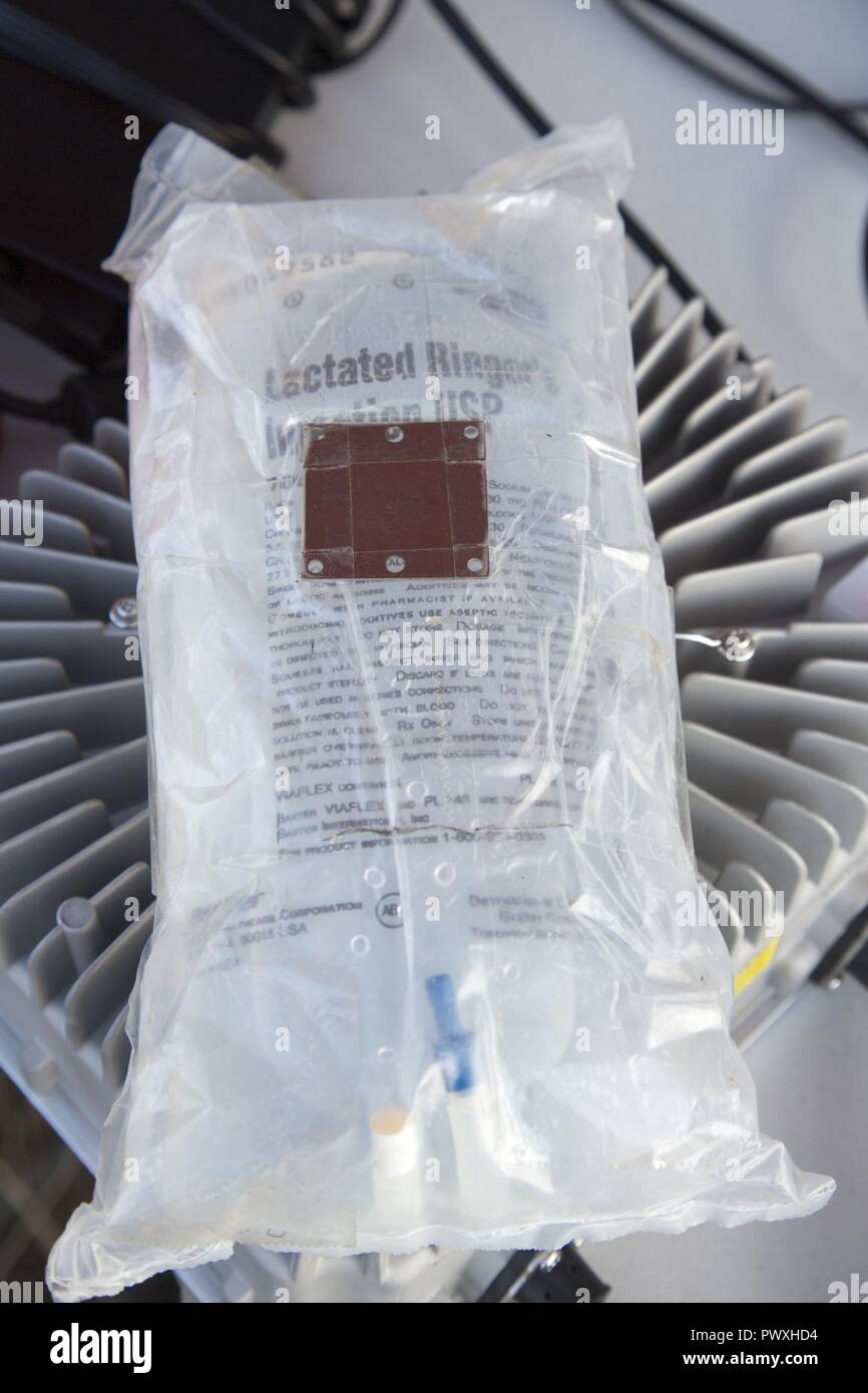 An IV-solution bag equipped with a metal plate is being prepped to be loaded on a Joint Tactical Aerial Resupply Vehicle (JTARV) for transport from a simulated forward operating base to a Marine special operations company in the field aboard Marine Corps Base Camp Pendleton, Calif., July 7, 2017. The JTARV, which is in the developmental phase, is a lightweight autonomous vehicle that provides an aerial resupply capability for immediate support to operational units. It was being tested as a resupply platform for machine-gun sustainment training with a cargo unmanned logistics system (C-ULS) dur Stock Photo