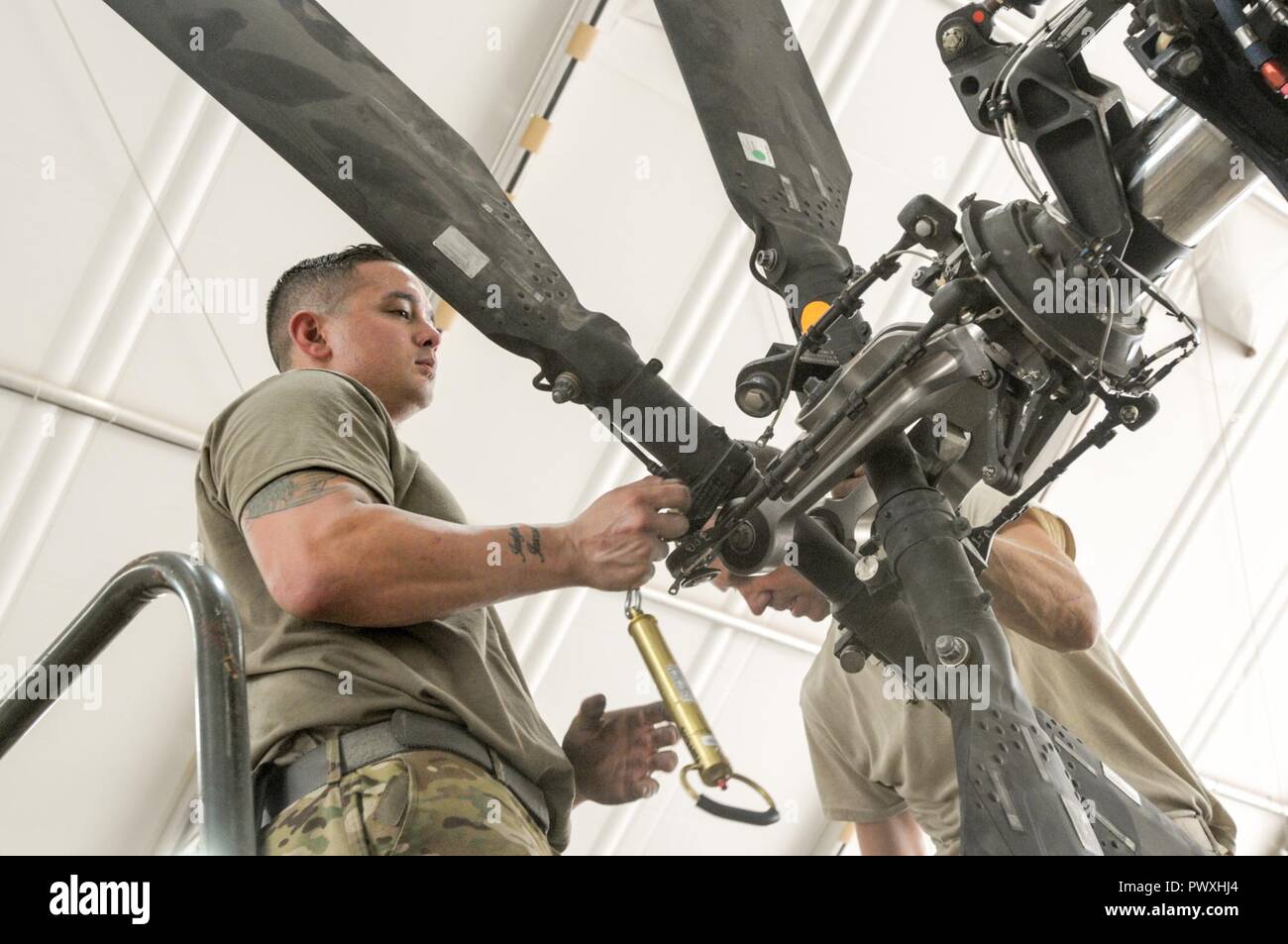 CAMP TAJI MILITARY COMPLEX, Iraq – Sgt. Johnathan Orbe an armament electrical avionic system repairer with the 449th Aviation Support Battalion, 29th Combat Aviation Brigade, works on attaching the tail rotor blades on the AH-64E Apache helicopter during the 500-hour Phase Maintenance cycle at Camp Taji Military Complex, Iraq, July 6, 2017. Proper maintenance ensures that the AH-64E Apache continues to provide reconnaissance and attack capability in the fight against ISIS for Combined Joint Task Force – Operation Inherent Resolve. CJTF-OIR is the global Coalition to defeat ISIS in Syria and Ir Stock Photo