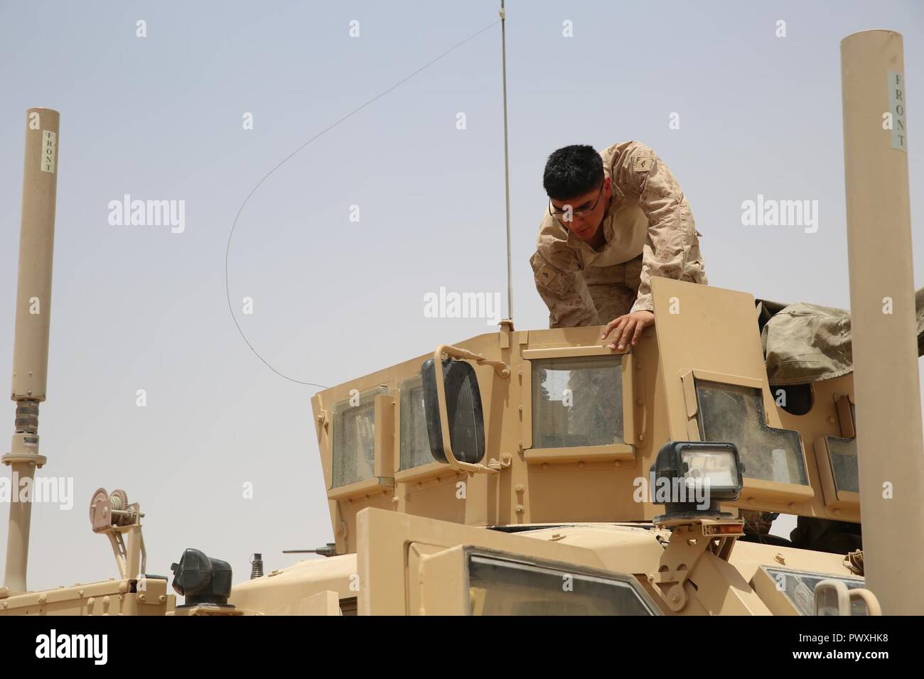 U.S. Marine Corps Lance Cpl. Arturo Barron, a mortarman assigned to Task Force Al Asad, with 1st Battalion, 7th Marines, Special Purpose Marine Air-Ground Task Force-Crisis Response-Central Command, inspects a .50-caliber machine gun in the turret of a mine-resistant, ambush-protected all-terrain vehicle while at Al Asad Air Base, Iraq, July 5, 2017. These Marines are part of the Task Force’s coalition security force team in charge of providing security to the base and personnel onboard. Task Force Al Asad’s mission is to advise and assist and build partner capacity with the Iraqi Security For Stock Photo