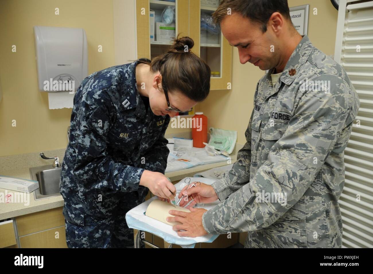 Dr. (Maj.) William Bynum (right), 11th Medical Group, advises Dr. (Lt.) Mary Beth Ray, Family Medicine Residency Program, on how to simulate placing a hormone implant into a patient’s arm June 13, 2017 at the Fort Belvoir Community Hospital, Va. The implant is a birth control method administered to some of the adolescent and adult, a key patient population treated by the hospital's family medicine residents and faculty. Stock Photo