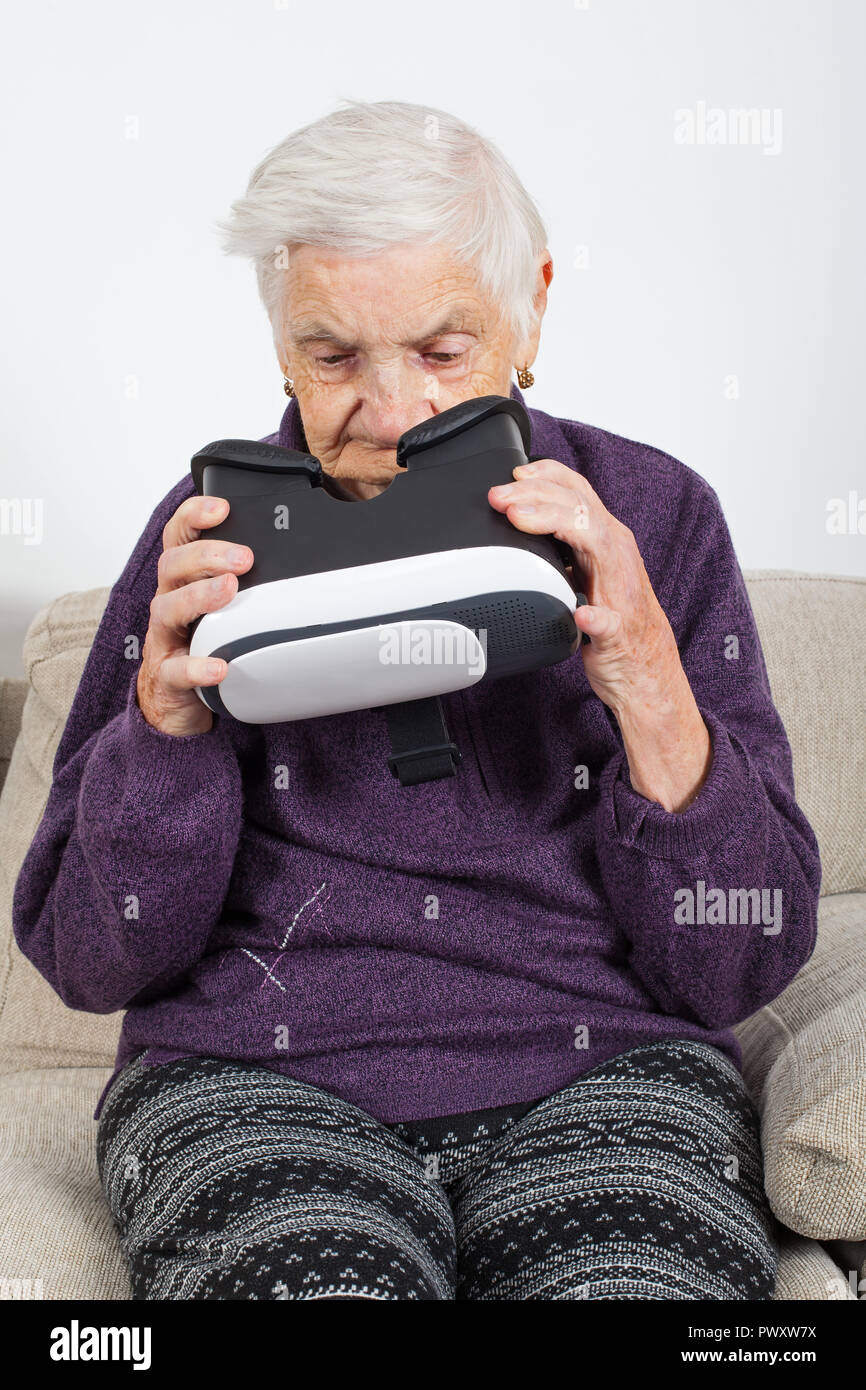 Elderly retired woman experiencing virtual reality video with headset Stock Photo