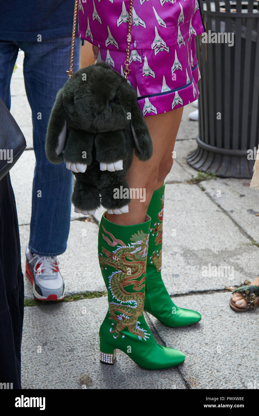 MILAN, ITALY - SEPTEMBER 21, 2018: Woman with rabbit puppet bag, green boots with dragon and pink satin dress before Blumarine fashion show, Milan Fas Stock Photo