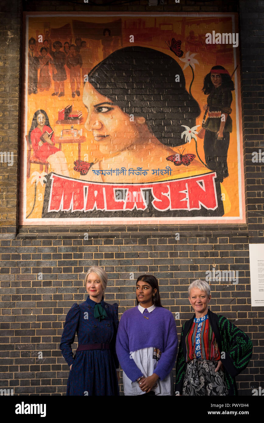 London, UK.  18 October 2018.  (L to R) Justine Simons, Deputy Mayor for Culture and Creative Industries, artist Justine Sehra and Tate Director Maria Balshaw in front of a newly unveiled artwork in Brick Lane.  The artwork features human rights activist Mala Sen and is one of 20 newly-commissioned artworks known as LDN WMN, designed by the London Tate Collective team, Tate’s group for 16 to 25 year old artists, which will appear in public spaces across the city marking the centenary of women’s suffrage.    Credit: Stephen Chung / Alamy Live News Stock Photo