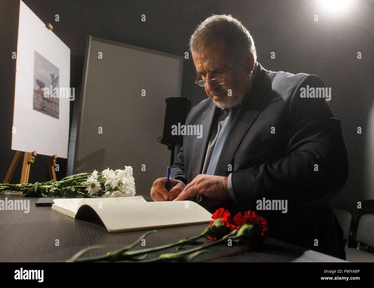 Refat Chubarov, leader of the Crimean Tatar national movement in Ukraine and worldwide is seen signing a condolence book as a sign of mourning to the victims of the attack during the commemoration. Commemorating the victims of an 18-year-old student who strode into his vocational college in Kerch in the Crimea, then pulled out a shotgun and opened fire, killing about 20 students and teachers and wounding about 74 others before killing himself, according the media. Stock Photo