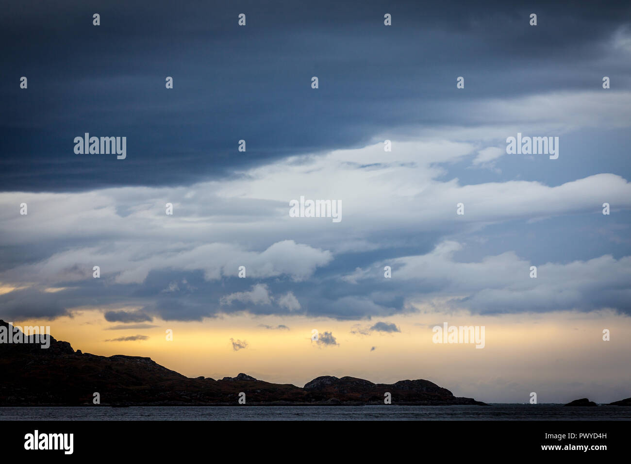 Layers of grey clouds above a rocky horizon Stock Photo
