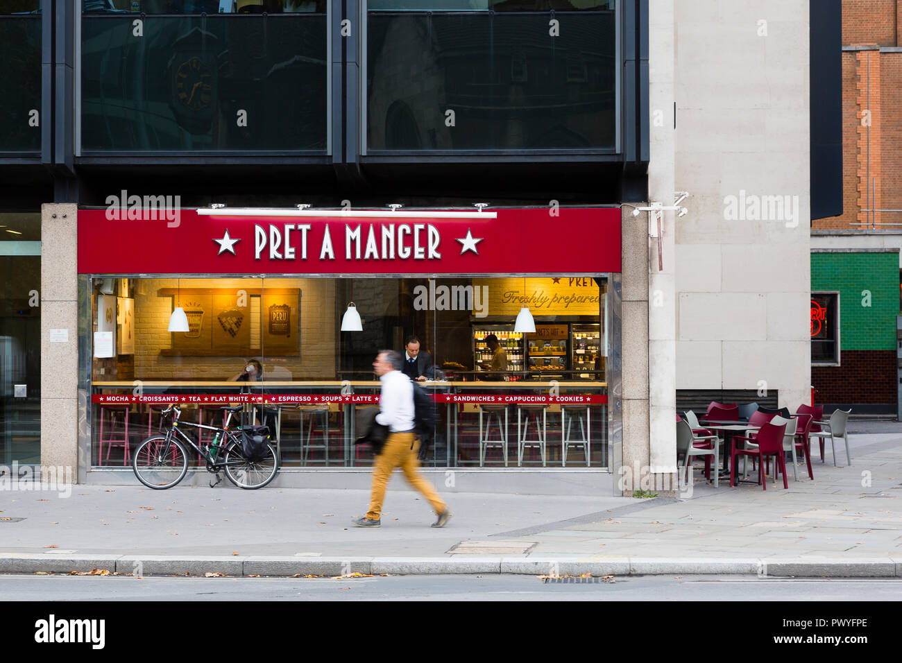 London, UK. A man in mustard trousers walks past a quiet branch of Pret a Manger. Stock Photo