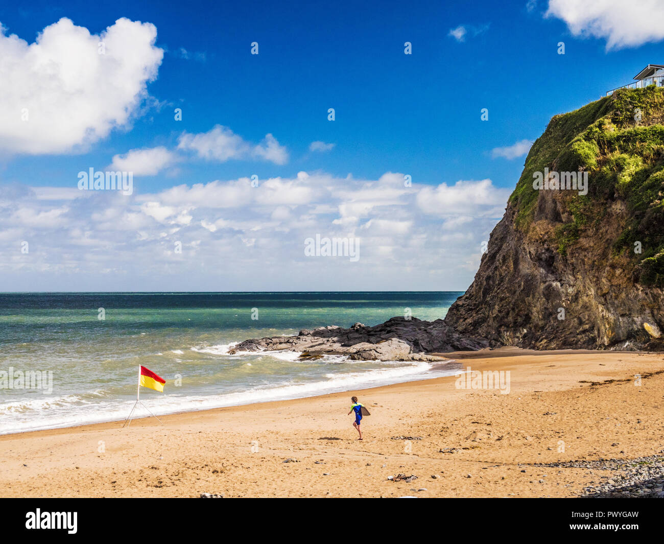 Child running to the sea at Tresaith beach on the Welsh coast in Ceredigion. Stock Photo