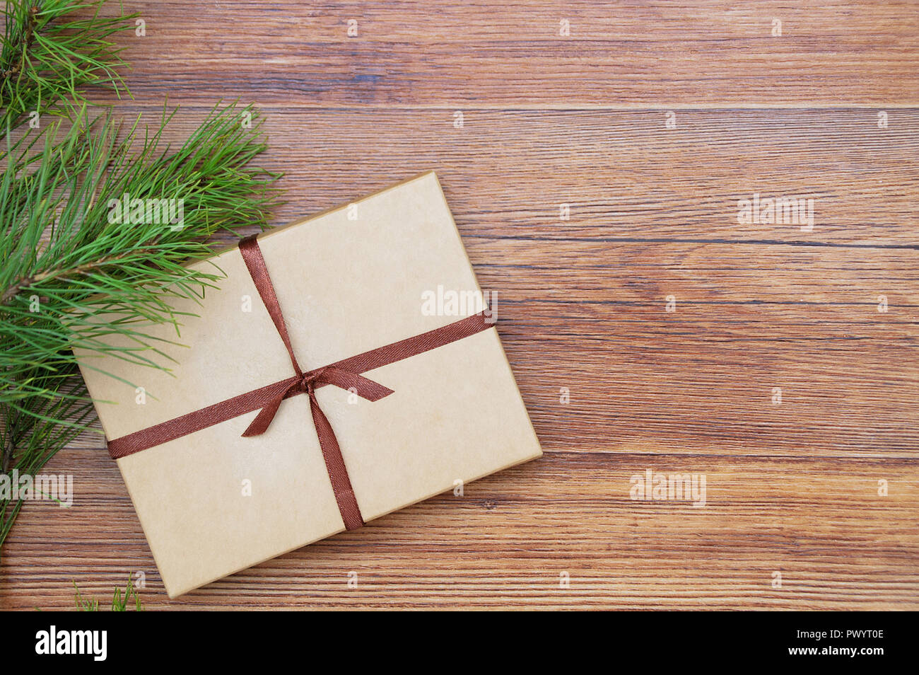 Christmas gift in a kraft box with ribbon on a brown wooden background. Place for text Stock Photo