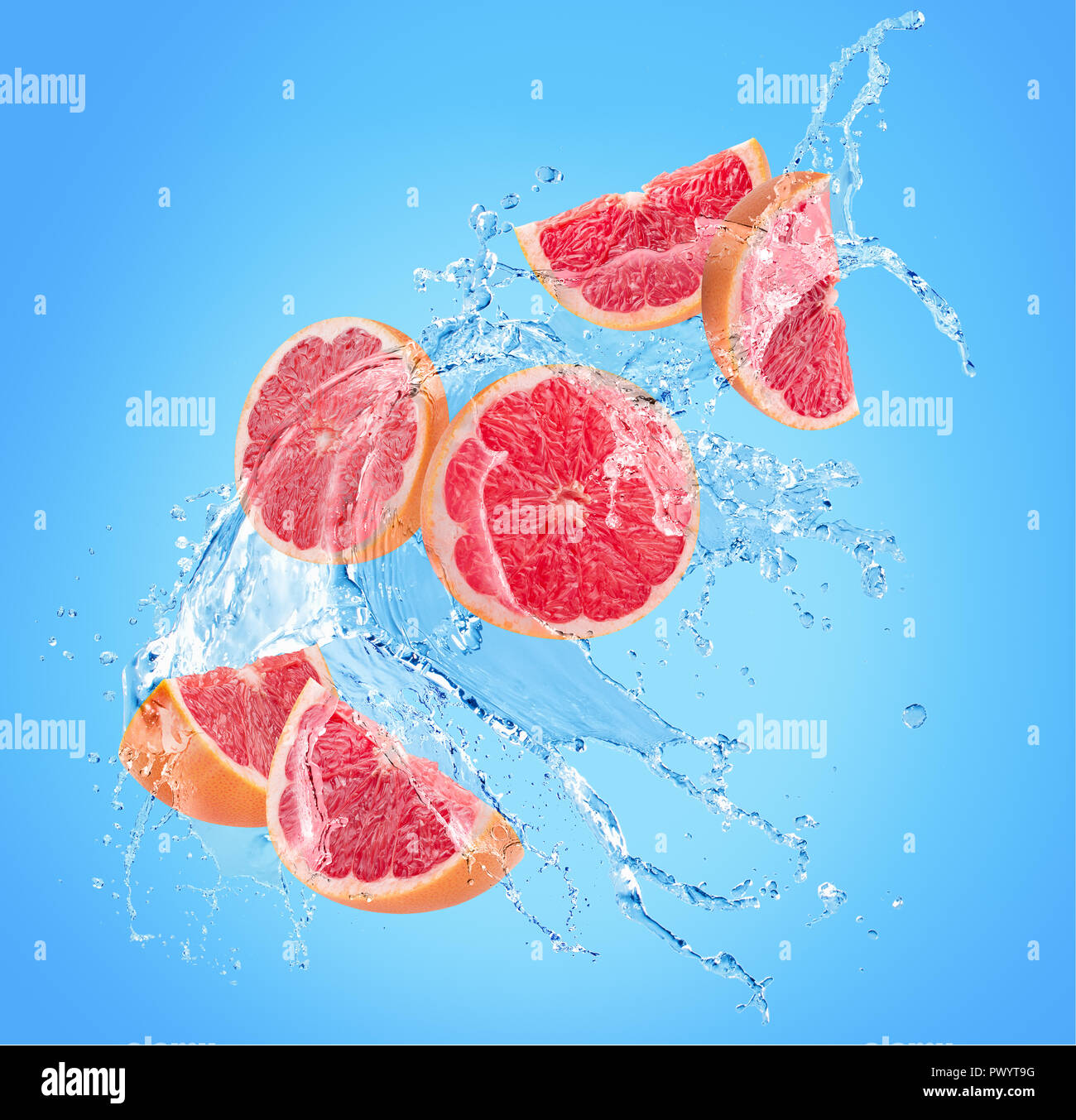 grapefruit slices in water splash on a blue background. Stock Photo
