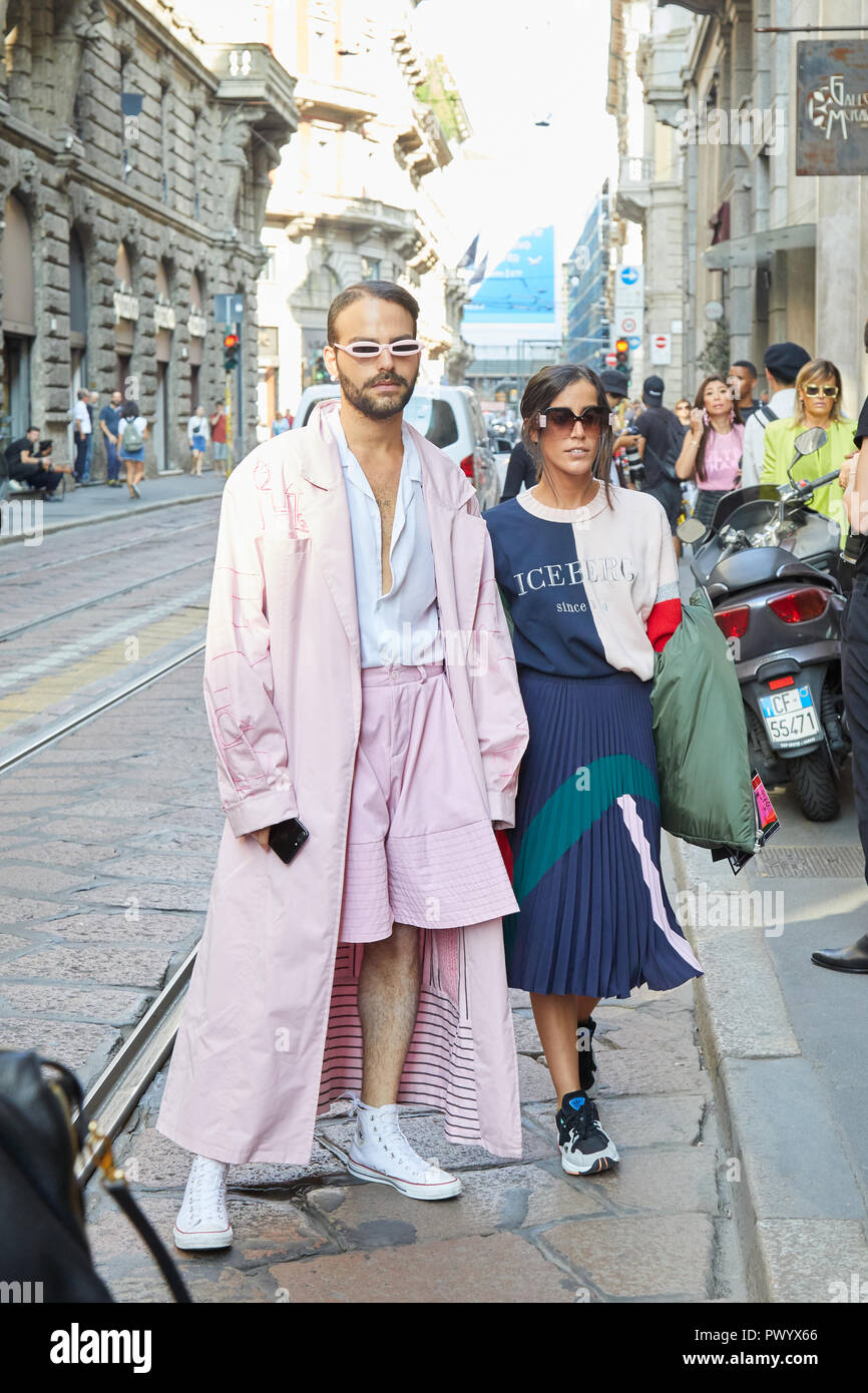 MILAN, ITALY - SEPTEMBER 21, 2018: Man with pink long coat and woman with Iceberg sweater before Iceberg fashion show, Milan Fashion Week street style Stock Photo