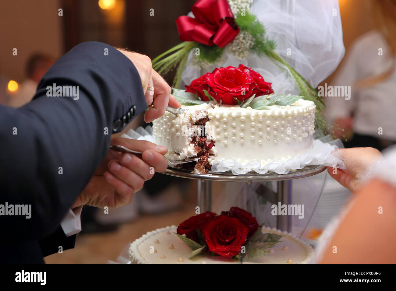 Groom cutting the wedding cake on the wedding party Stock Photo