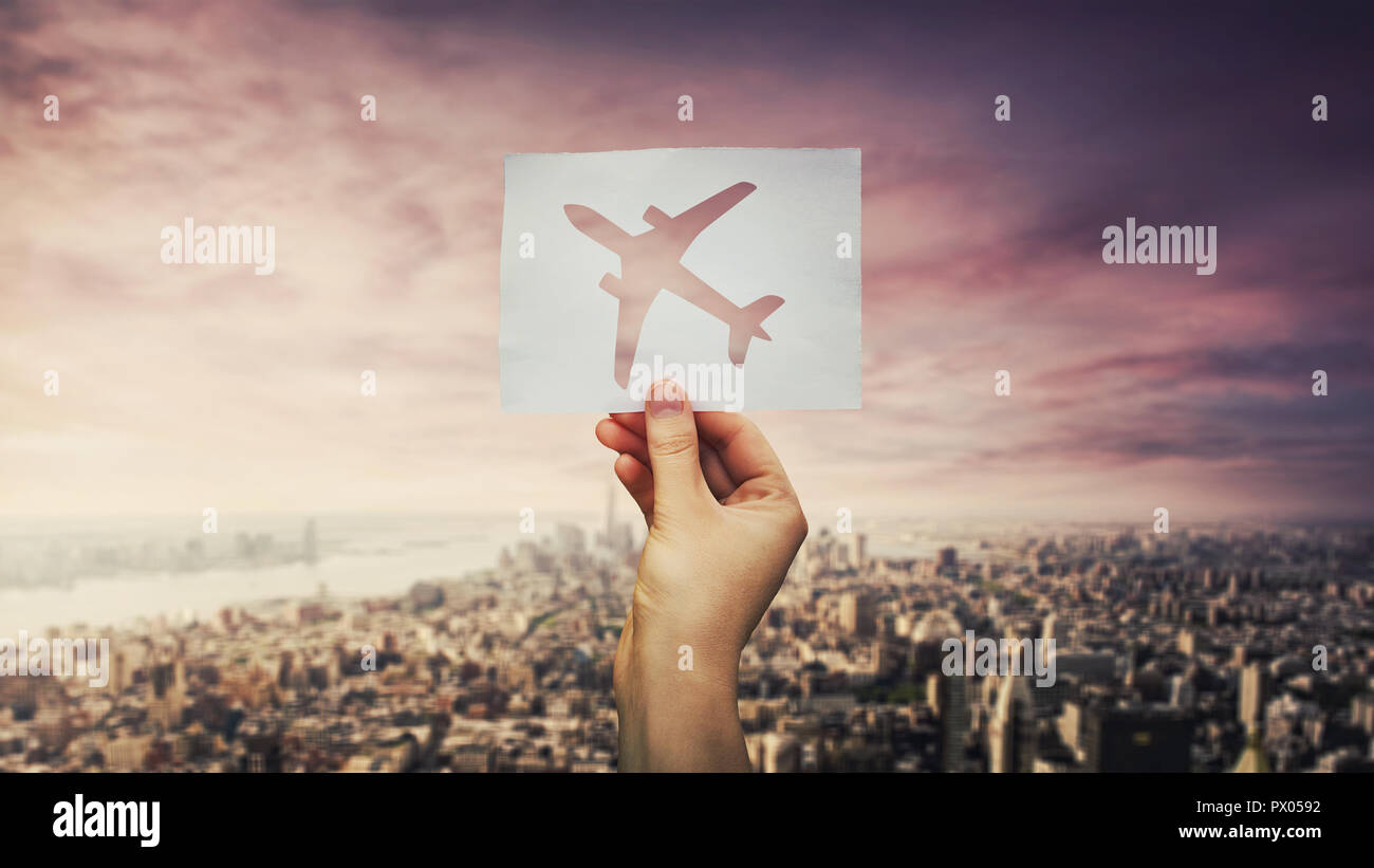 Woman hand holding a white paper sheet with airplane icon over big city ...