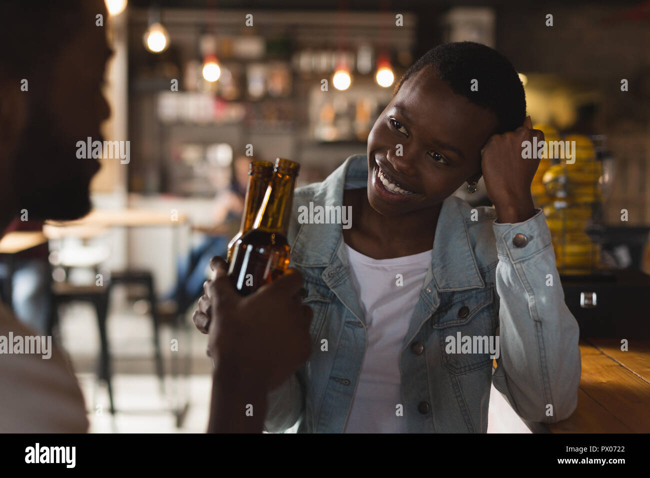 Couple toasting beer bottle in cafe Stock Photo
