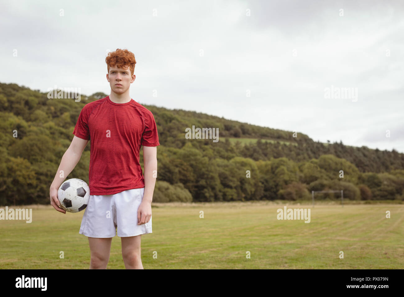 Football player standing with soccer ball in the field Stock Photo