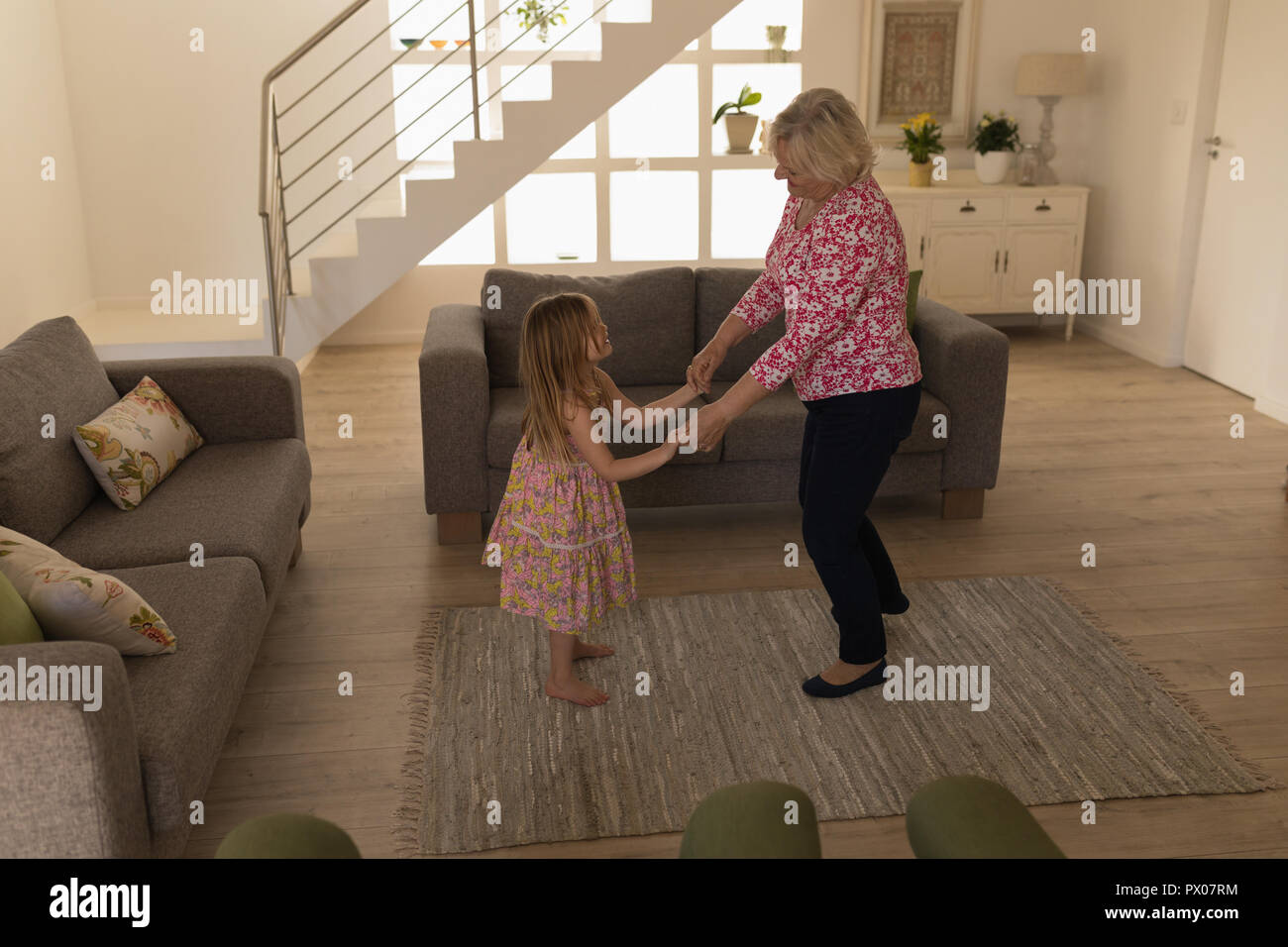 Grandmother and granddaughter dancing in living room Stock Photo