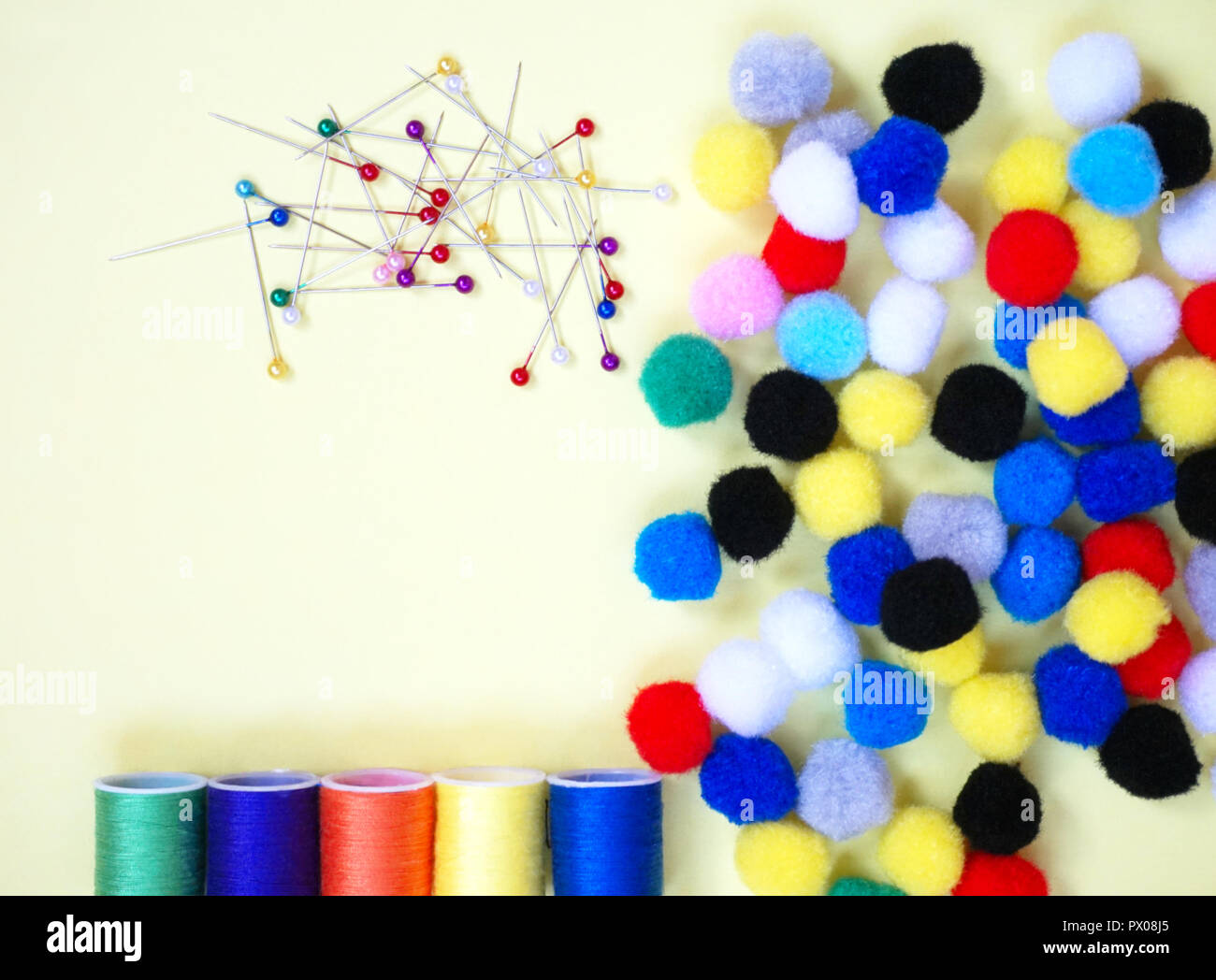 Pins, cotton threads and mini pom-poms, sewing accessories in different vivid color Stock Photo
