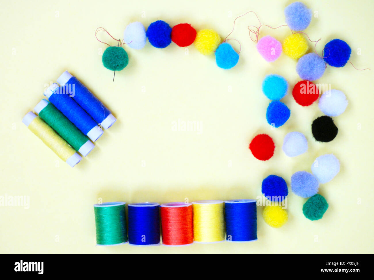 Sewing accessories in different colors, threads, needle and pompons, flat lay Stock Photo