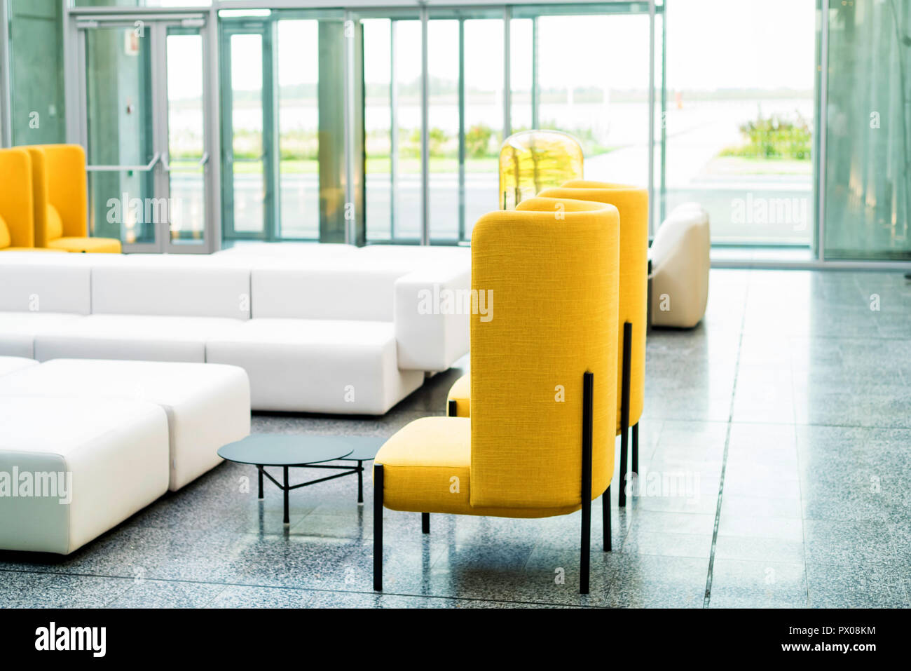 Office waiting area interior with white sofas and yellow chairs Stock Photo