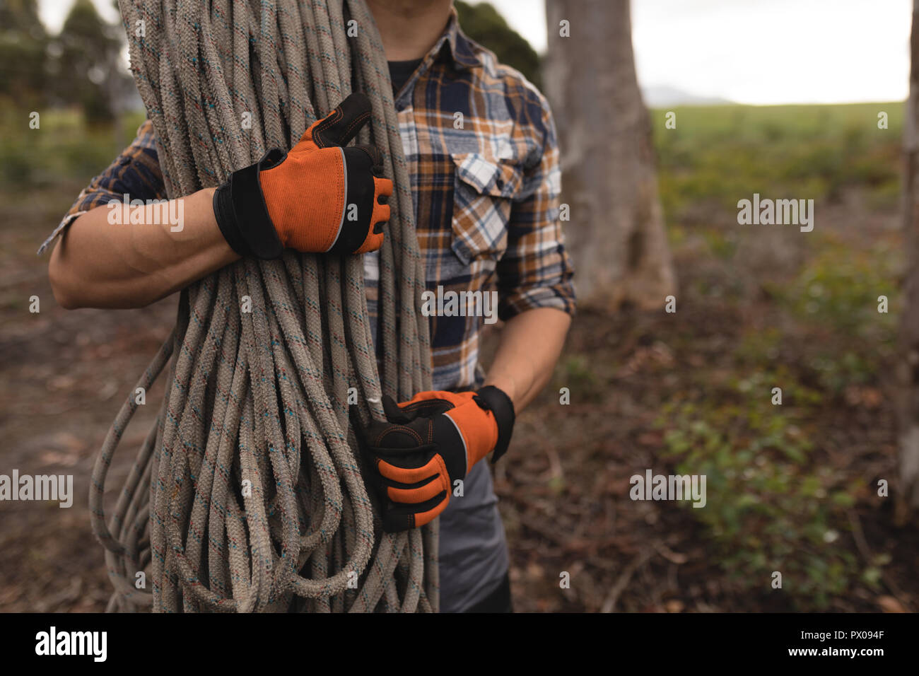 Lumberjack holding rope in forest Stock Photo