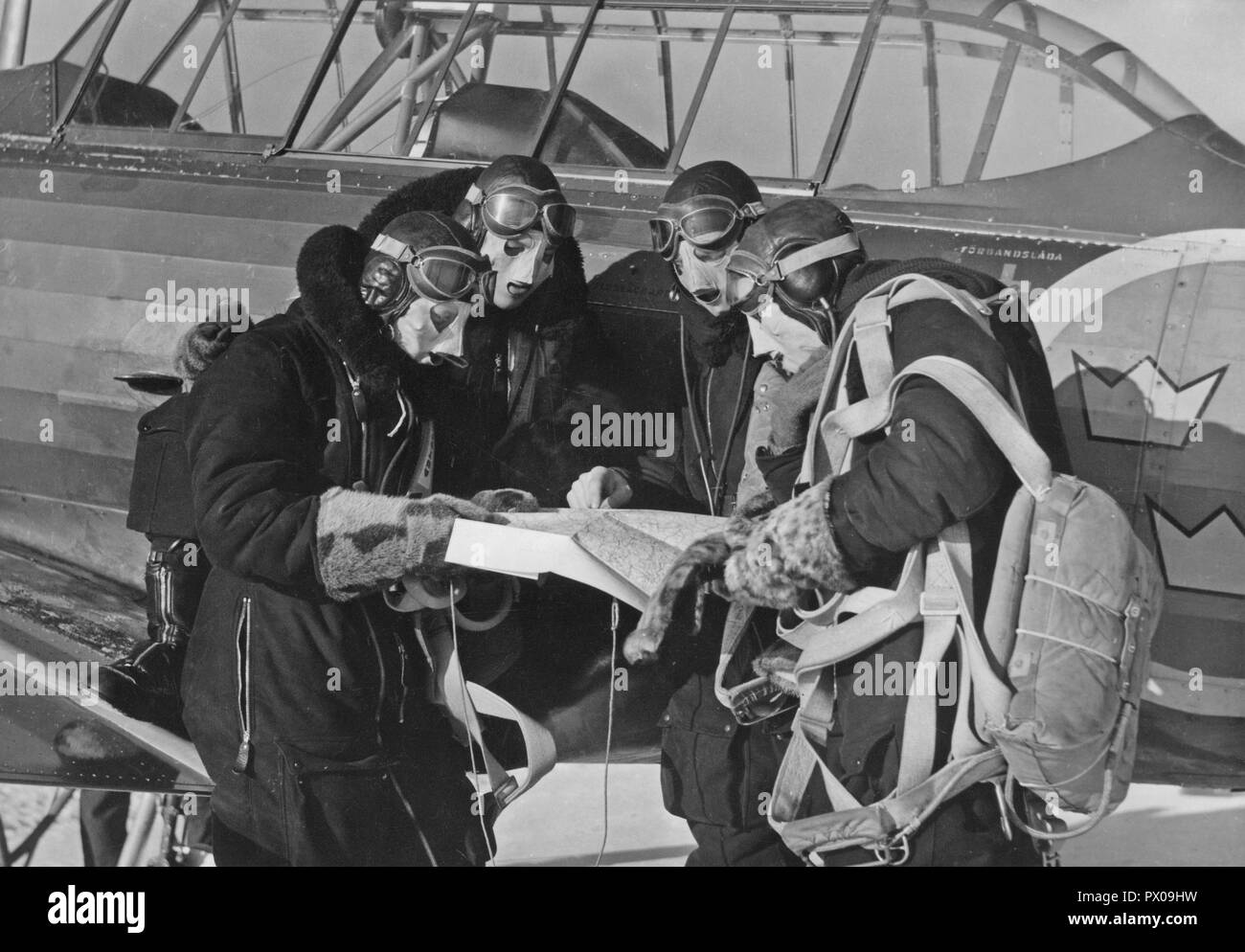 Pilots in the 1940s. A group of swedish pilots are studying the map together prior their flying assignment. They are pilots at the swedish airforce school of pilots at Grangärde. Sweden February 1942 Stock Photo