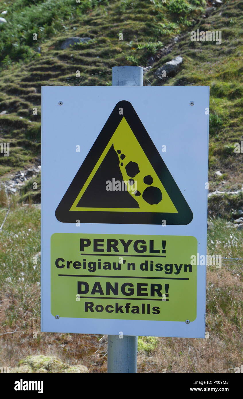 Sign in English and Welsh warning of rockfalls, Snowdonia National Park, Gwynedd, North Wales, United Kingdom Stock Photo