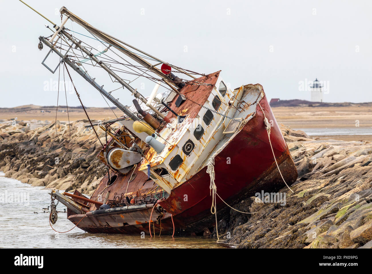 An abandoned derelict fishing boat stranded on a rock jetty Stock Photo ...