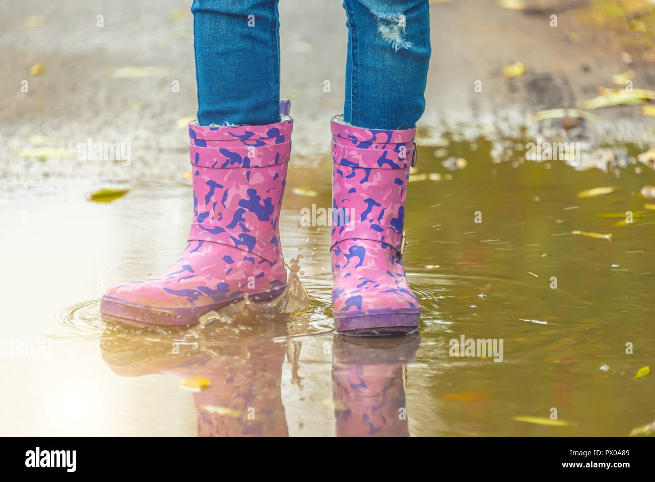 children's feet in rubber boots stand in a puddle in the autumn Stock ...