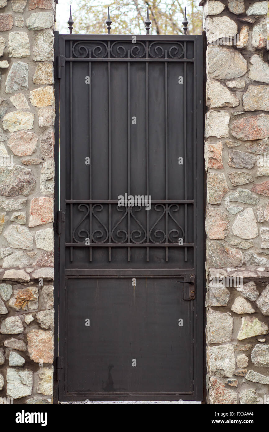 Black metal door with stone wall. Antique looking of urban architecture