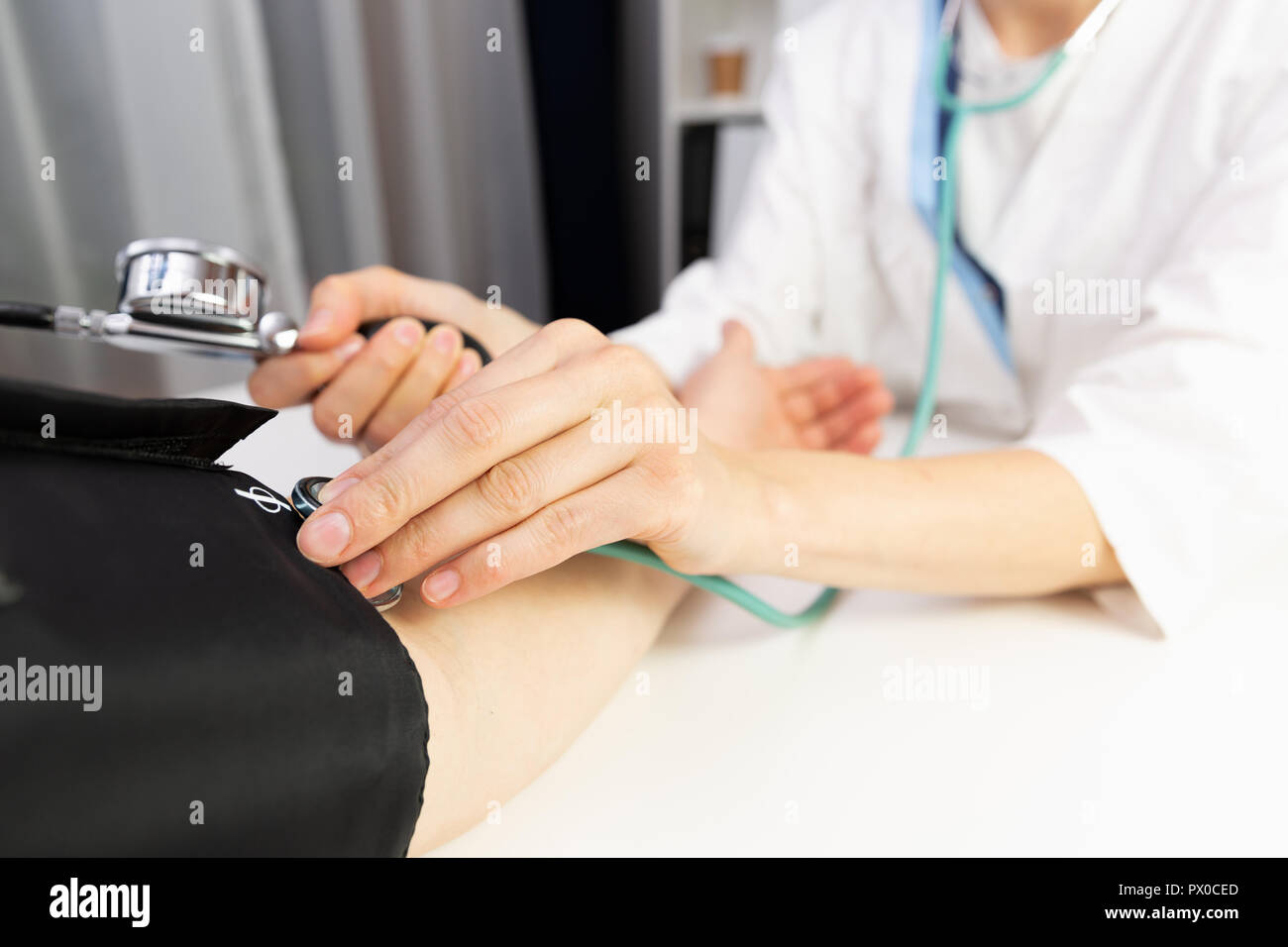 A female doctor measuring blood pressure of a man in a doctors office. Stock Photo