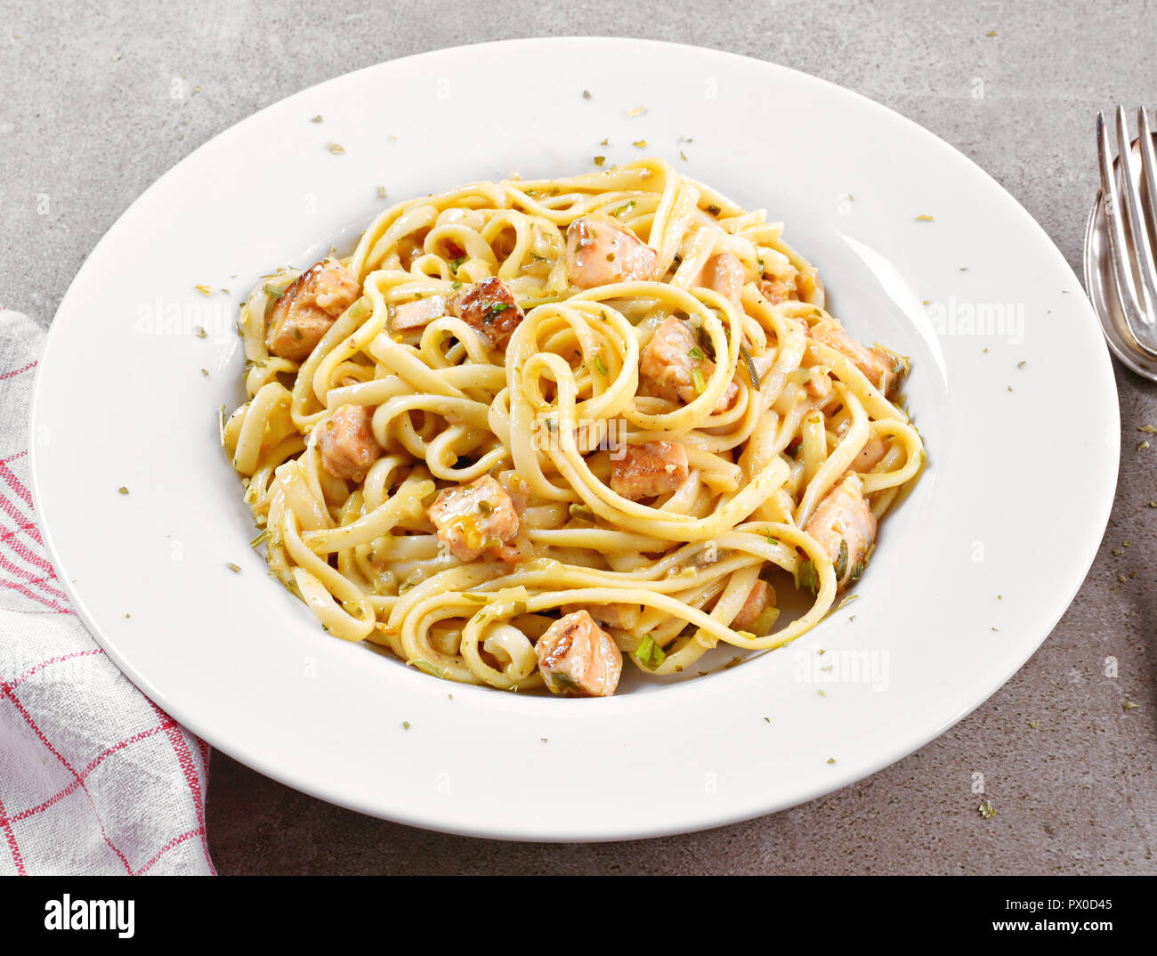Delicious salmon pasta dish, tagliatelle or linguine noodles. High angle view of fresh spaghetti pasta with herbs and grilled salmon. Stock Photo
