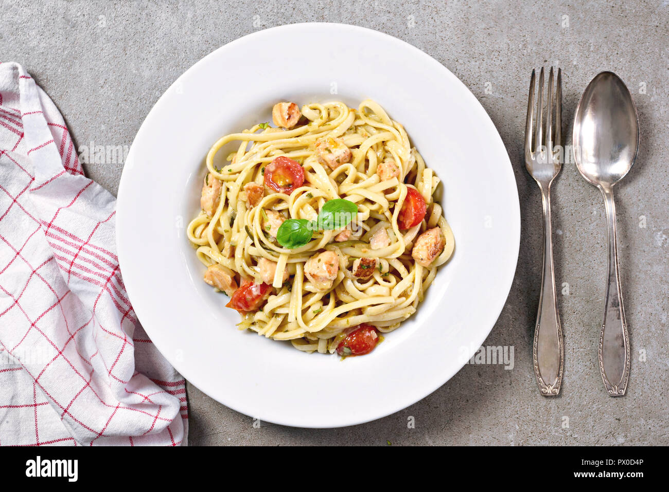 Delicious salmon pasta dish, tagliatelle or linguine noodles. High angle view of fresh spaghetti pasta with herbs and cherry tomatoes. Stock Photo