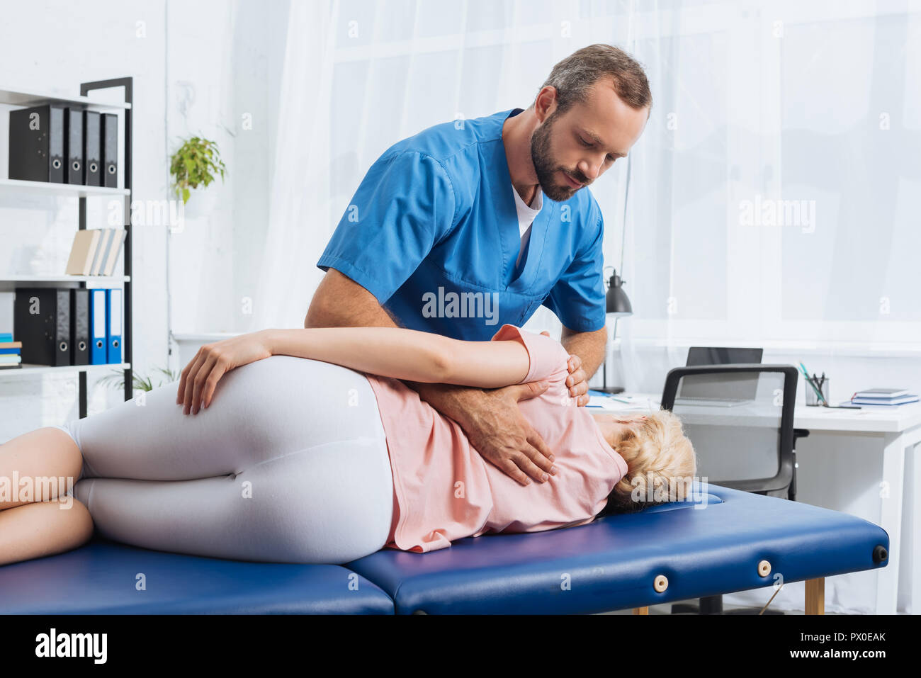 chiropractor massaging back of patient that lying on massage table in hospital Stock Photo