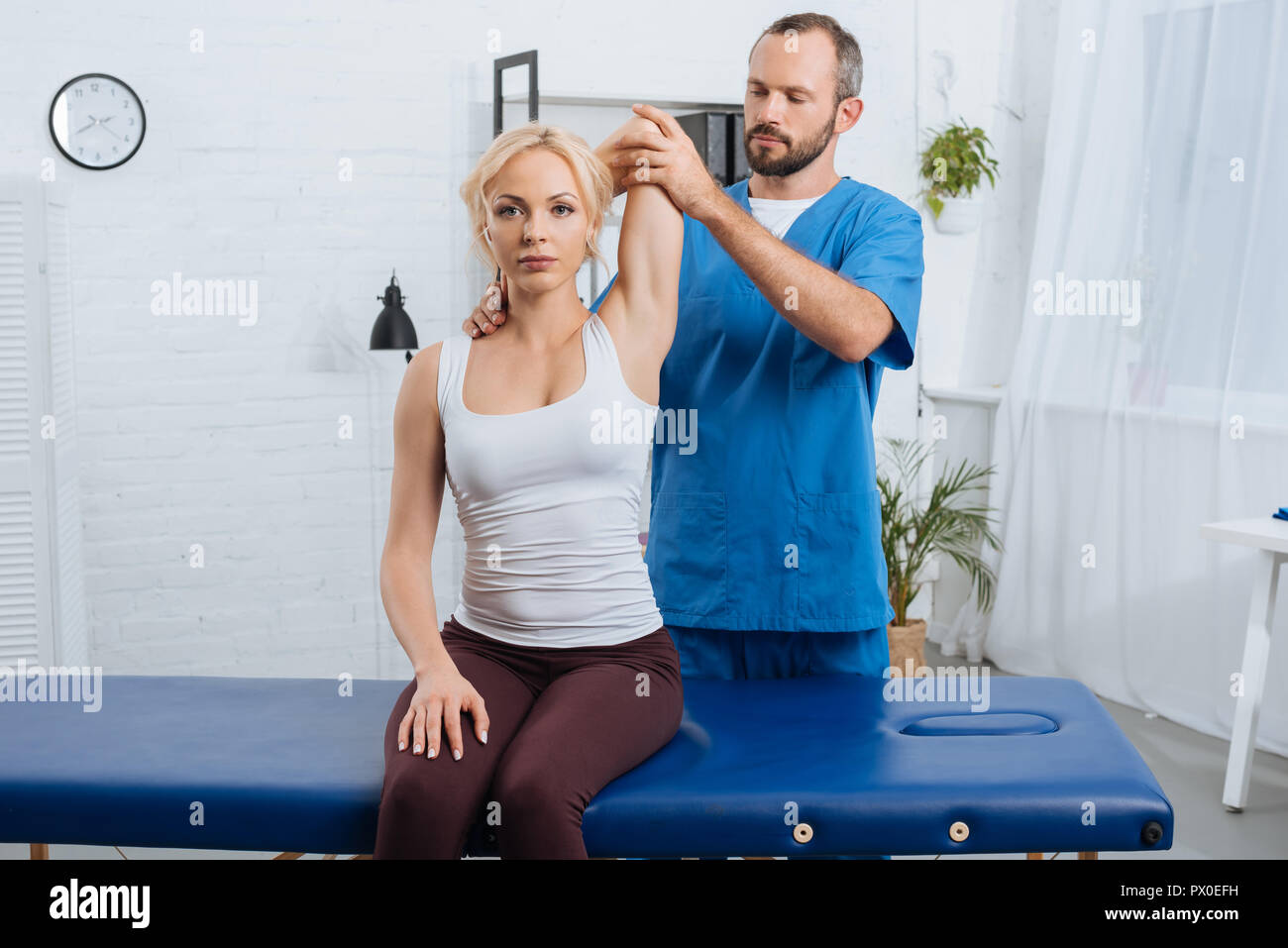 portrait of chiropractor stretching womans arm on massage table in