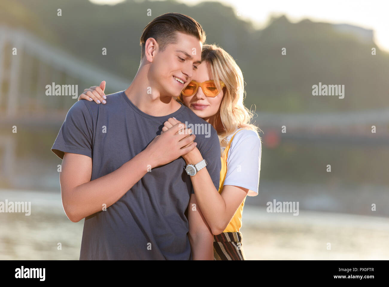 girlfriend hugging boyfriend on river beach in evening Stock Photo