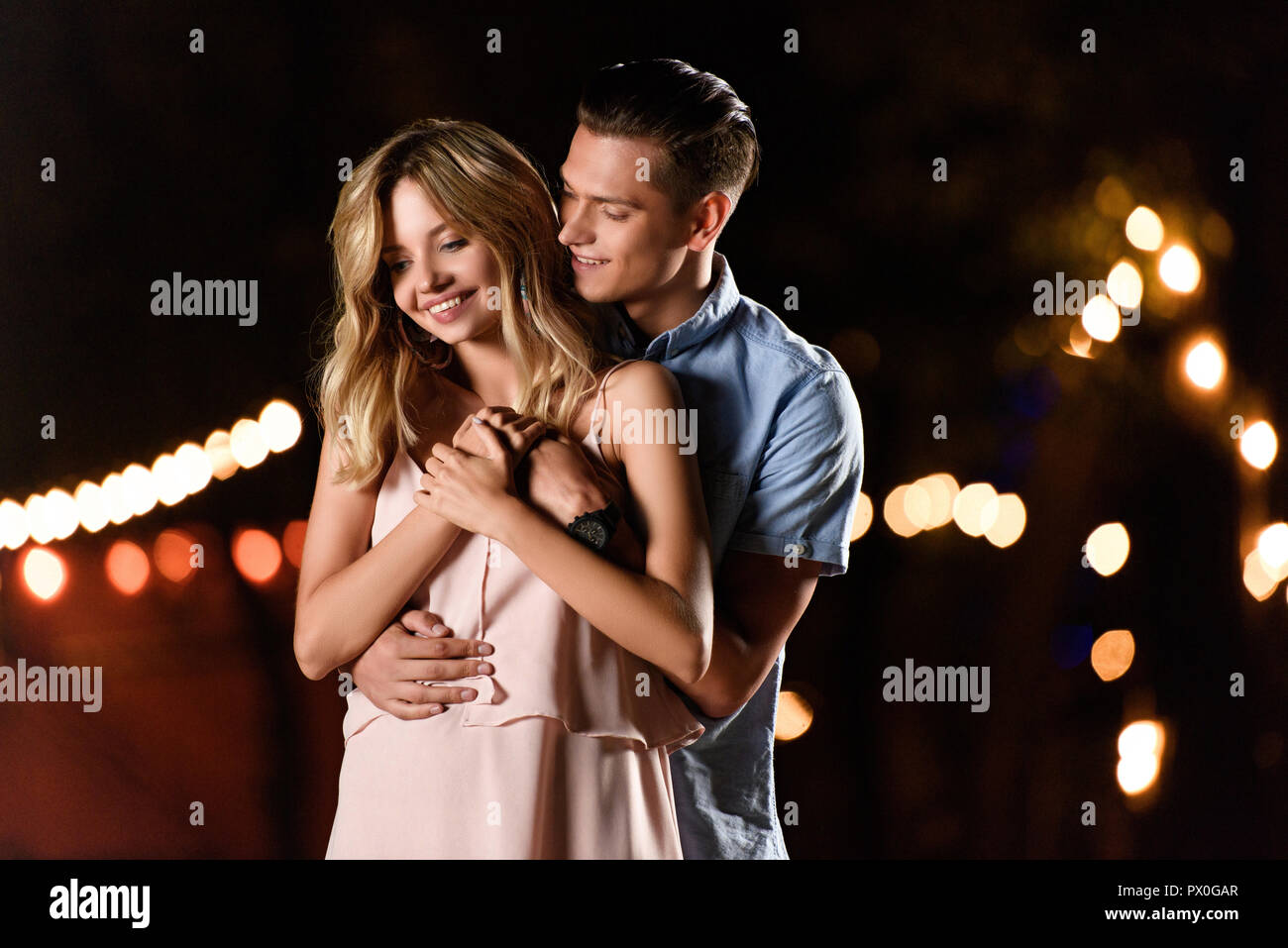boyfriend hugging smiling girlfriend on river beach in evening Stock Photo