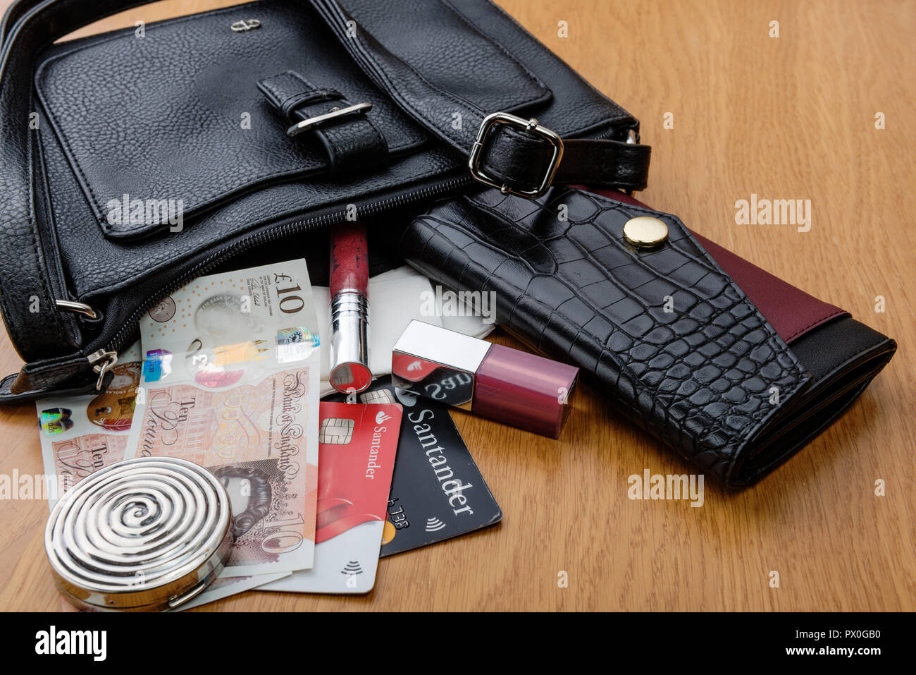 Women's handbag and purse, the contents emptied out. Showing some cosmetics, cash and bank cards. Stock Photo