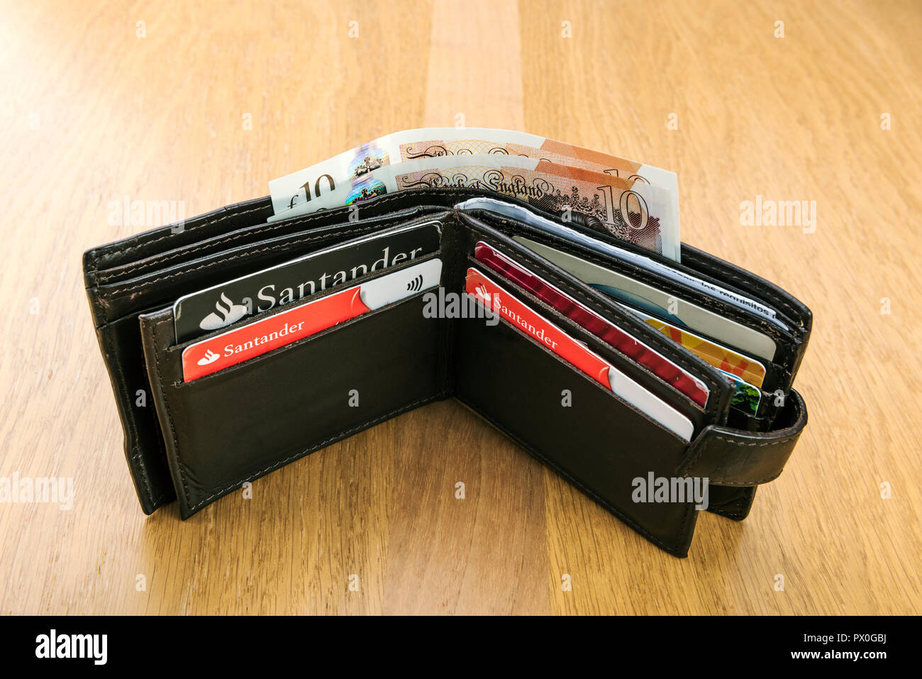 Mans old leather wallet with credit cards and pound sterling banknotes ...