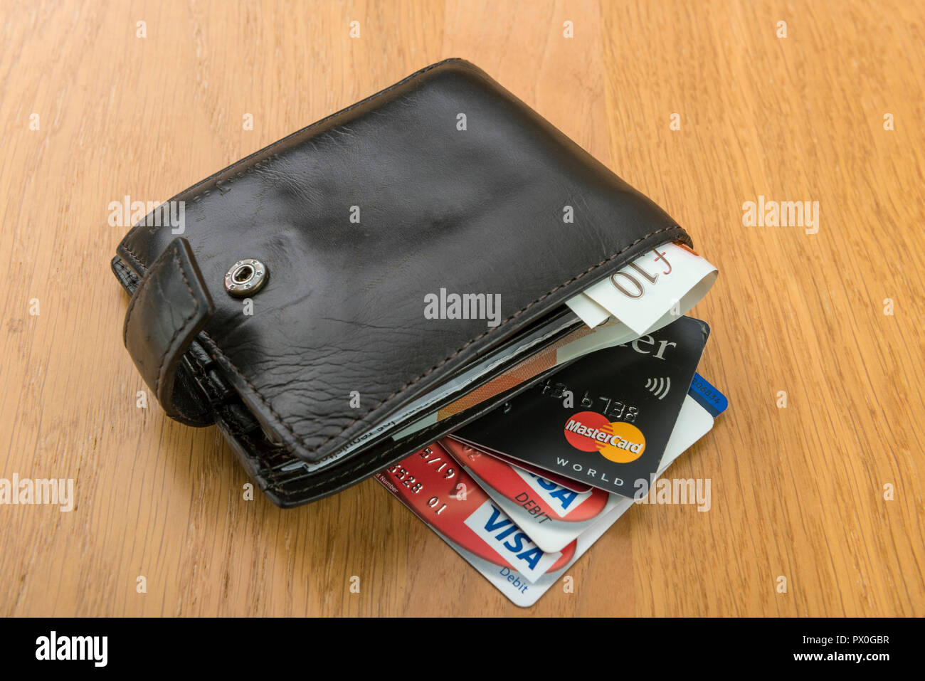 Mans old leather wallet with credit cards and pound sterling banknotes ...