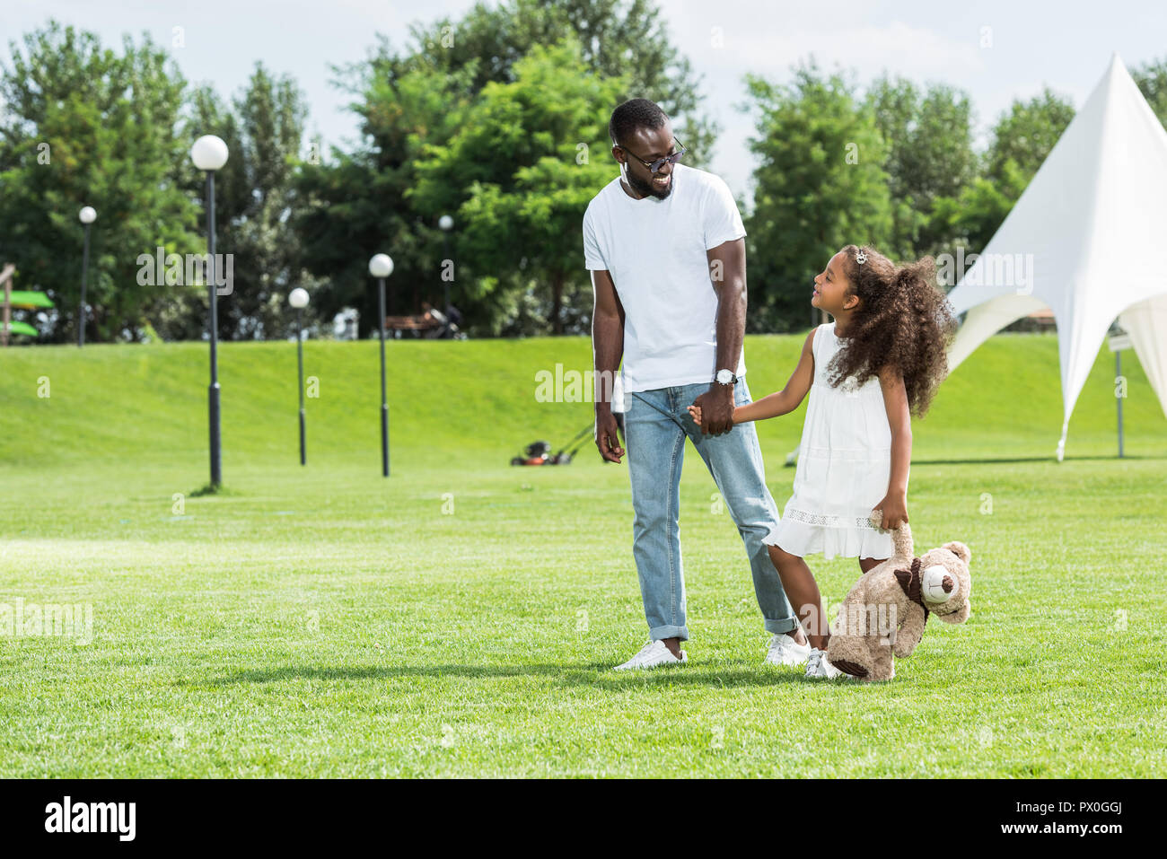 african american father and daughter with teddy bear holding hands and ...