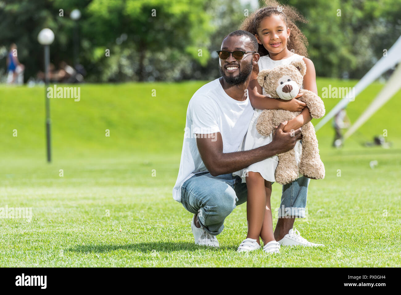 Папа стоящую дочку. Обнимает ребенка на корточках. Фото здорового отца американца с дочкой. Отец обнимается с дочкой сидя на корточках. Отец присел на дочь.