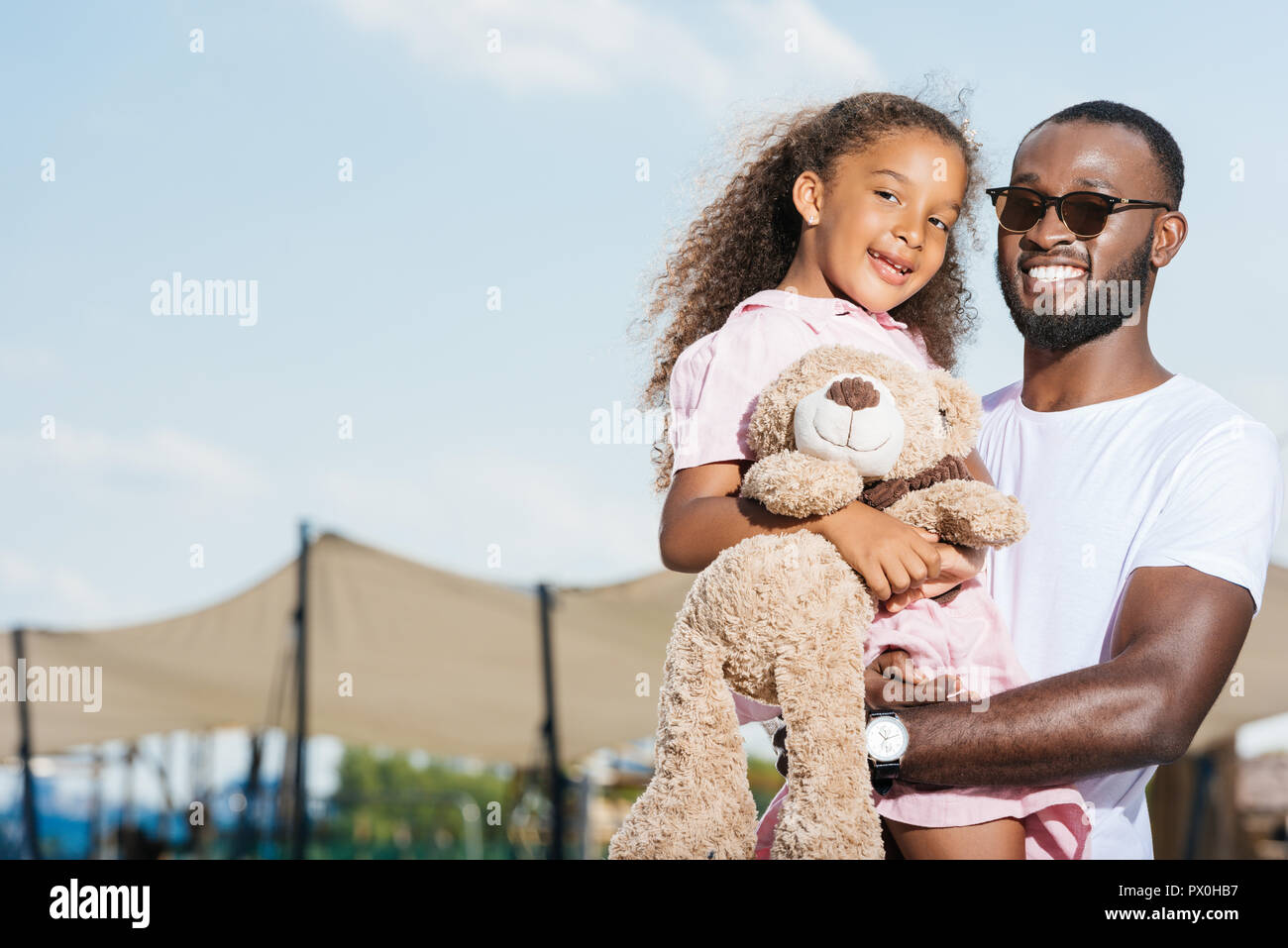 smiling african american father holding daughter and they looking at ...