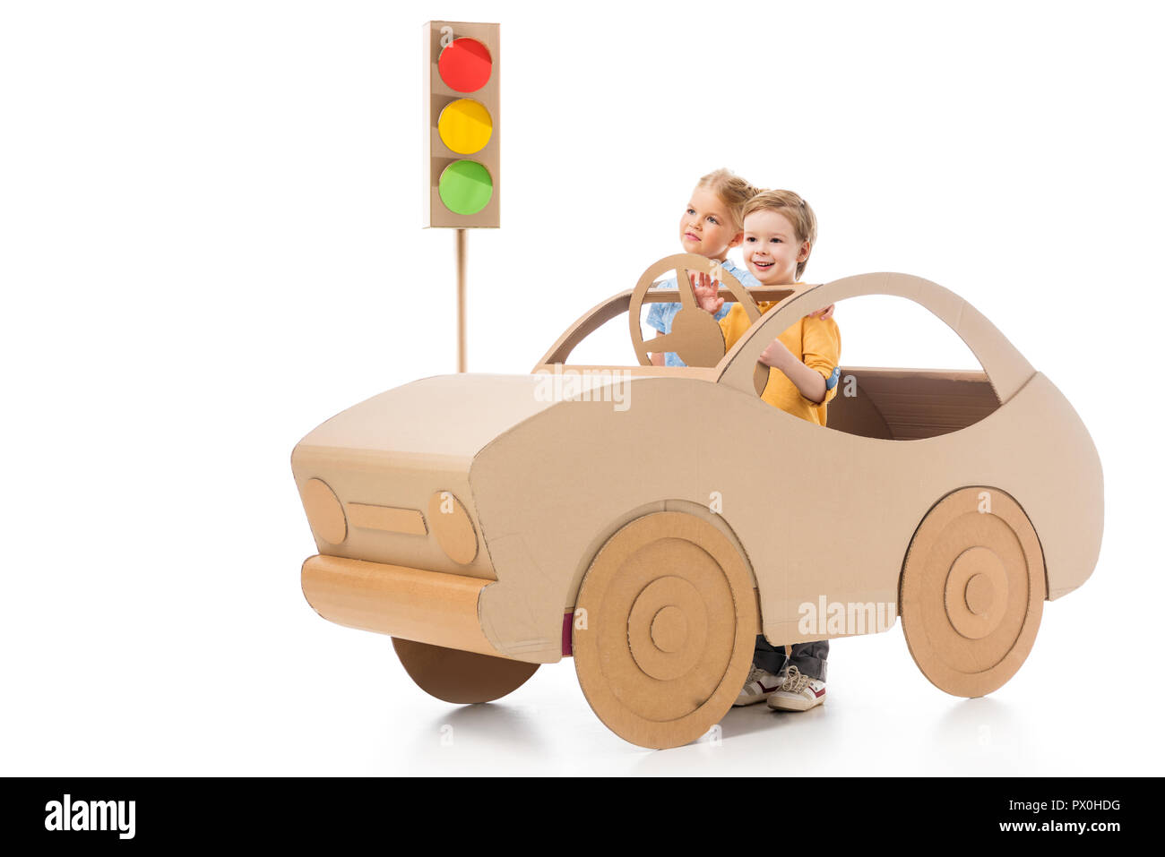 brother and sister playing with cardboard car and traffic lights, on white Stock Photo
